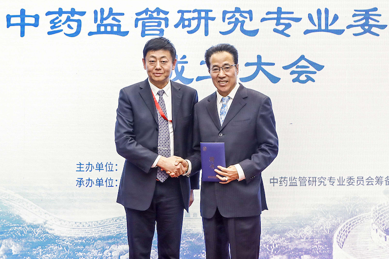 The president of the CSDR, Wei Zhang, shakes hands with the chairman of the newly established pharmacovigilance committee, Guoqing Li